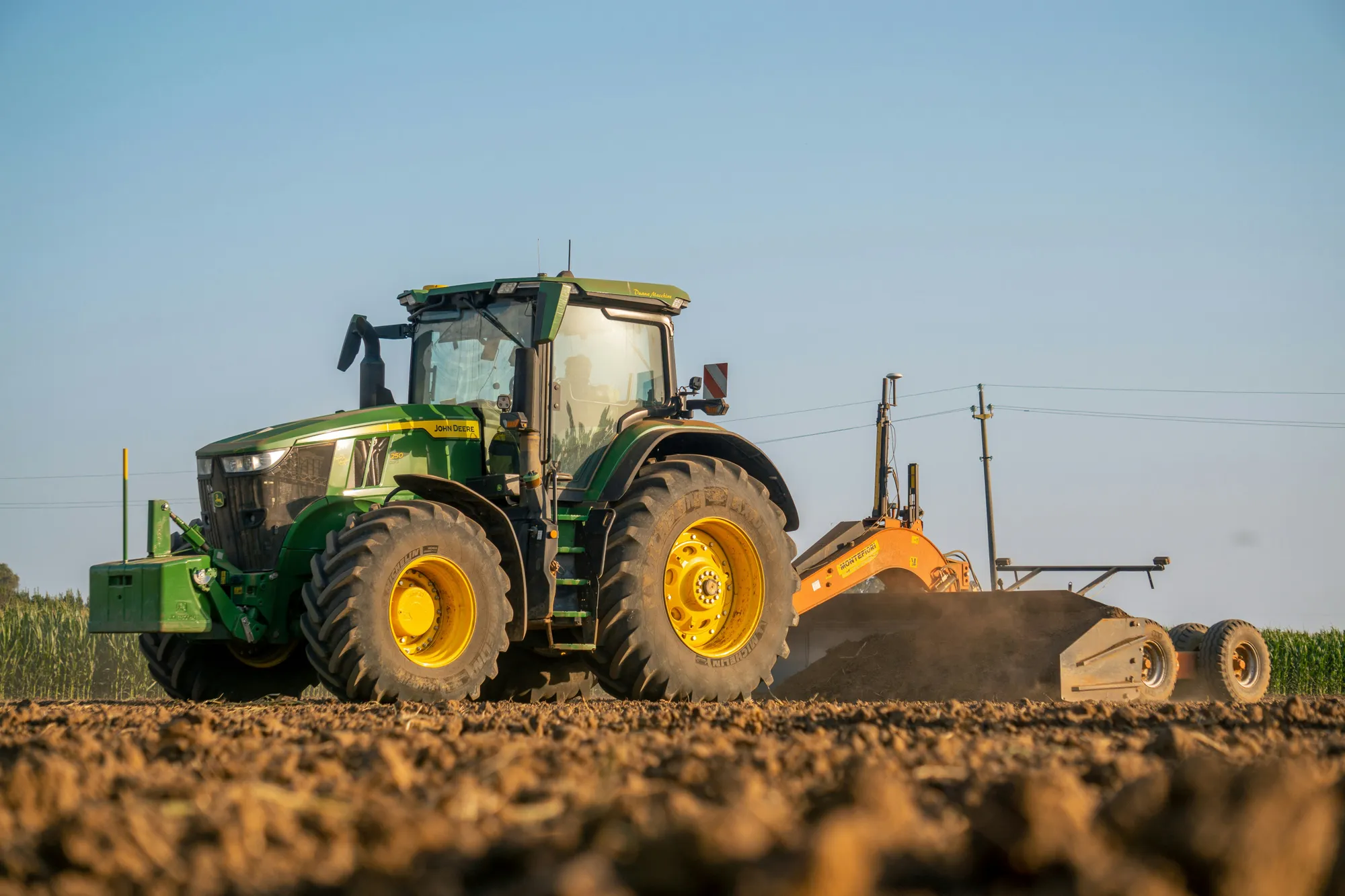 A tractor preparing soil in a field at sunrise